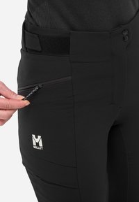 Pantalons de randonnée en mil pourpre avec une poche zippée, une ceinture à velcro et un détail de logo. Matière texturée avec une coupe ajustée.