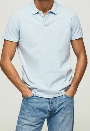 Hellblaues Poloshirt mit kurzen Ärmeln, zwei-Knopf-Leiste und kleinem Logo auf der Brust, kombiniert mit blauen Jeans.