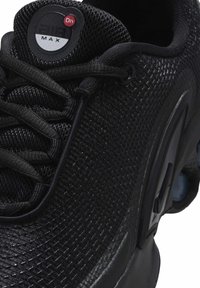 Artimas juodų Nike Air Max batų vaizdas, kuriame matosi tekstūruotas tinklelis, raišteliai ir Air Max ženklas ant liežuvėlio.
