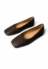 Pair of dark brown woven leather flat shoes with rounded square toes and tan inner lining on white background.