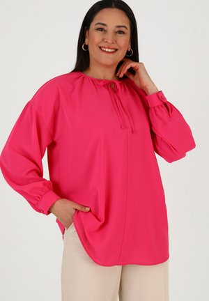Blusa rosa brillante con maniche lunghe e puffate e scollatura annodata. Presenta una vestibilità ampia e tasche laterali, realizzata in un tessuto morbido.