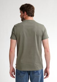 Olijfgroene T-shirt met korte mouwen en een ronde hals, gemaakt van zachte stof. Heeft een rechte zoom en een eenvoudig, minimalistisch ontwerp.