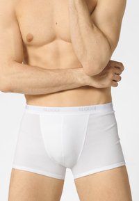 Boxer shorts bianchi in cotone con una vestibilità aderente, dotati di una morbida cintura elastica con la scritta "SLOGGI" in grigio chiaro. Texture liscia.