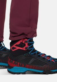 Stivali da esterno ad alte prestazioni con un design nero e rosso, con accenti blu, materiali testurizzati e lacci regolabili attorno alla caviglia.