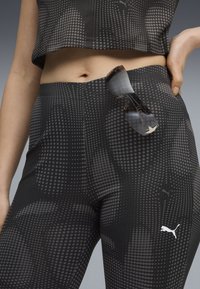 Black activewear set featuring a fitted crop top and high-waisted leggings with a dotted pattern, complemented by a pair of sunglasses resting on the waistband.