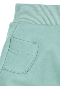 Muntgroene sweatpants hebben een geribde tailleband en een enkele achterzak met gestikte details, gemaakt van zacht textielmateriaal.