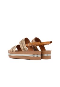 Brown platform sandals with woven upper, three straps, adjustable ankle strap, and metallic accent on the sole. Textured footbed for comfort.