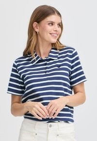 Marinblå och vit randig pikétröja med krage, featuring fem knappar och en liten hjärtlogotyp på bröstet. Bomullsmaterial, kort ärm. 
