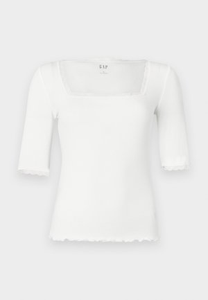 Hvit tettsittende topp med firkantet utringning og korte ermer. Har blonder langs nakkekanten og ermene. Laget av ribbet materiale.