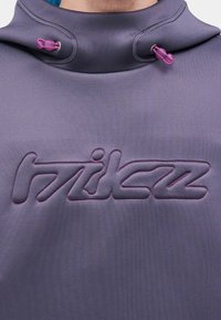 Tumedat hallist tekstuuriga kangast pullover-tüüpi kapuutsiga dressipluus, millel on silmatorkav lilla tikitud logo ja roosad reguleeritavad kaela paelad.