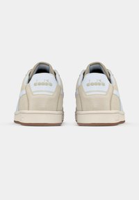 Αθλητικά παπούτσια από μπεζ σουέντ και λευκό δέρμα με σόλα από καουτσούκ, που διαθέτουν λογότυπο στη φτέρνα και αντίθετες ραφές.