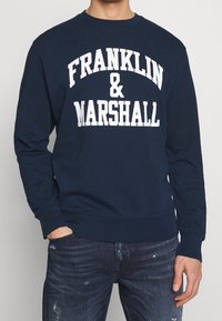 Felpa blu navy con scritta bianca "FRANKLIN & MARSHALL". Scollo tondo, maniche lunghe, polsini e orlo a coste. Tessuto morbido e strutturato.