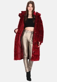 Piros kordbársony pufi kabát bolyhos belsővel, fémes ezüstszínű, testhezálló nadrággal párosítva. Fekete rövid felső és fekete bokacsizma egészíti ki a megjelenést.