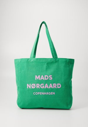 Bolsa de lona verde con dos asas para el hombro. Presenta un texto en rosa brillante: "MADS NØRGAARD COPENHAGEN" exhibido de manera prominente. Diseño sencillo.