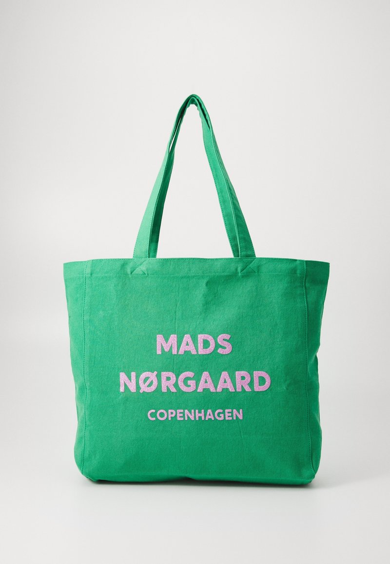 Sac fourre-tout en toile verte avec deux anses. Présente un texte rose vif : "MADS NØRGAARD COPENHAGUE" affiché de manière proéminente. Design simple.