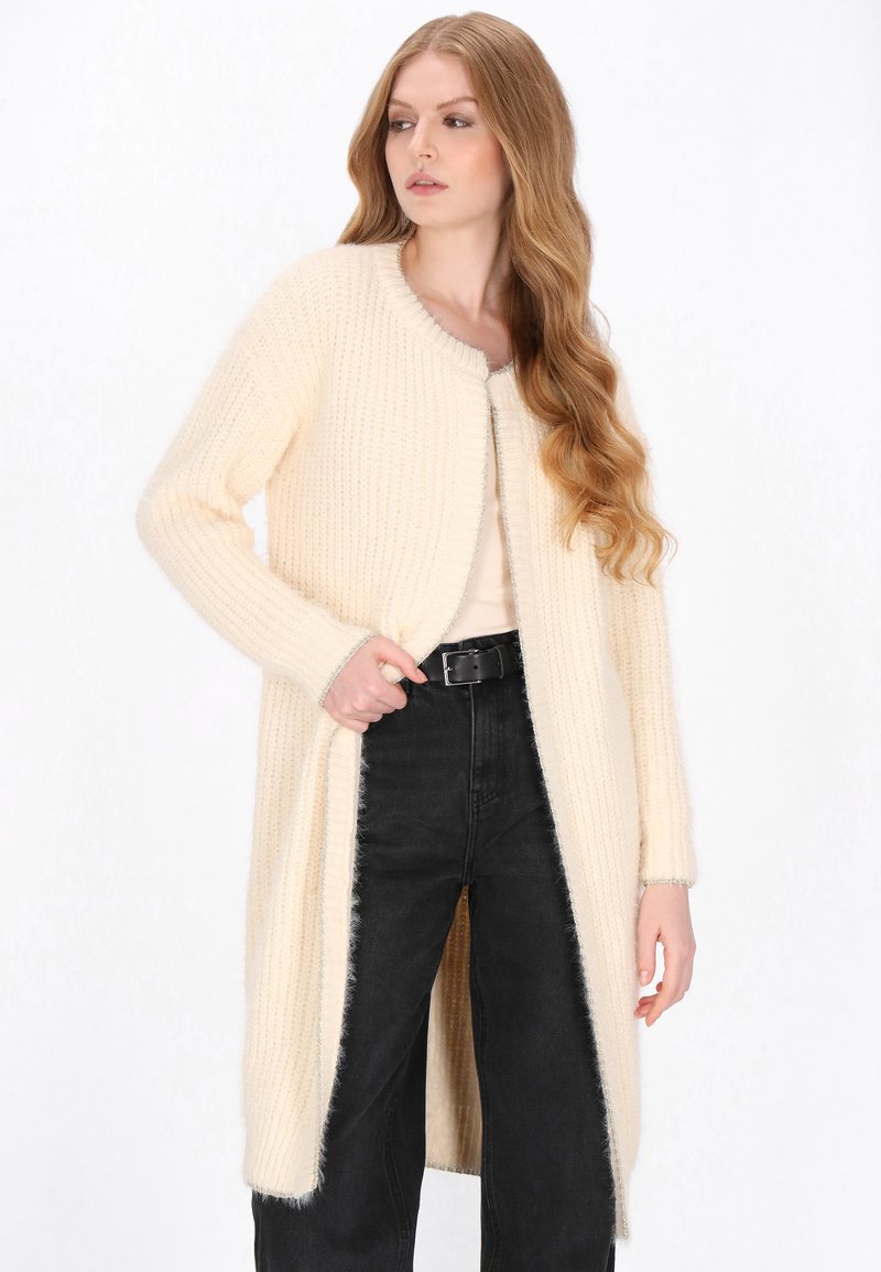 Cardigan lung, de culoare crem, tricotat, cu textură pe verticală, deschis în față și gât rotunjit. Are mâneci lungi și detalii de trim cu contrast.