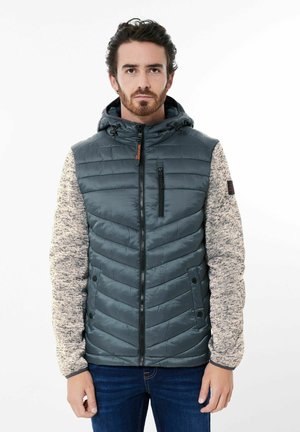 Padded Jacke mit einer dunkelgrauen Vorderseite und hellen strukturierten Ärmeln. Verfügt über einen Reißverschluss, eine Kapuze und dezente horizontale Nähte.