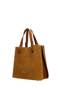 Hnědá semišová taška na rameno s dvojitými rukojetemi z texturované kůže a stříbrným kovovým logem na přední straně, zobrazená mírně z boku na bílém pozadí.