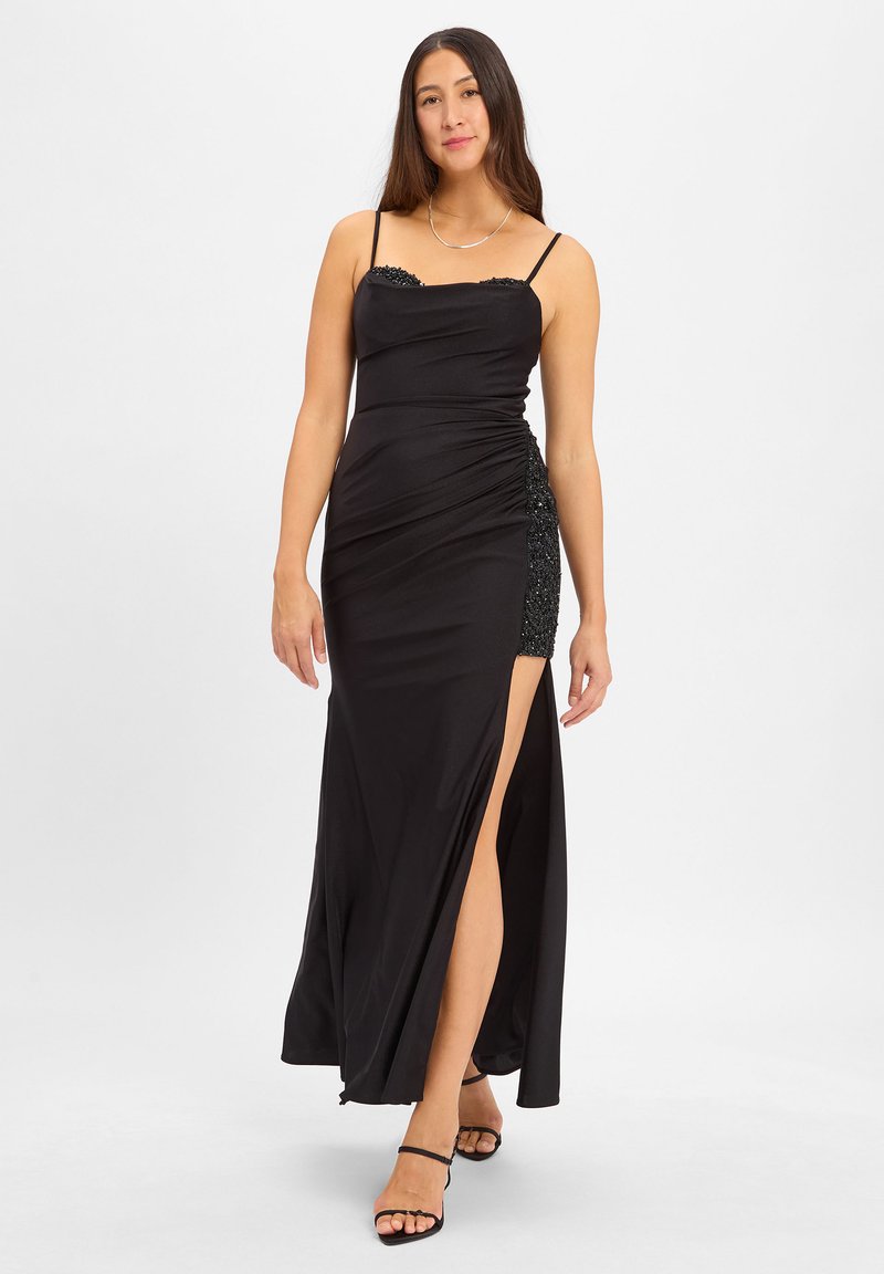 Schwarzes Abendkleid mit Spaghetti-Trägern, strukturiertem Oberteil, gerafftem Design, seitlichem Schlitz und einem verzierten Akzent an der Hüfte. Glatte Stoffoberfläche.