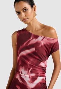 Punainen ja valkoinen sidontakuosinen mekko, jossa on epäsymmetrinen olkapäämuotoilu ja kerätty sivu yksityiskohta, valmistettu pehmeästä, joustavasta kankaasta.