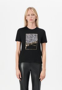 Black t-shirt featuring a leopard print graphic with gold accents, short sleeves, and a relaxed fit. Worn with black leather pants.