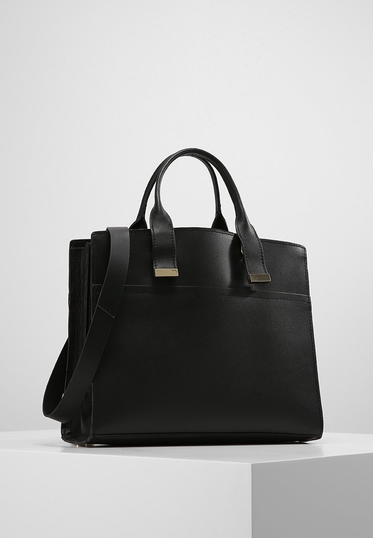 Svart läderhandväska med strukturerad design, dubbla handtag ovanpå, justerbar axelrem och en framficka med guldtonade detaljer.