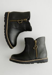 Schwarze Ankle Boots aus Kunstleder mit strukturiertem Finish, seitlichen Reißverschlüssen mit herzförmigen Zippern und robusten Gummisohlen.