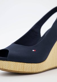 Sandalo a zeppa blu navy con punta scoperta, tomaia in tessuto e platform in juta intrecciata. Presenta un piccolo dettaglio del logo in rosso, bianco e blu.
