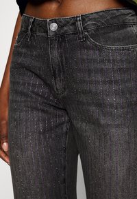 Gray denim jeans featuring vertical purple stripes and subtle sparkles. Standard waistband with button closure and pockets.