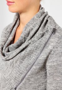Grauer Pullover mit einem Schal-Kragen und strukturiertem Strickmuster; verfügt über einen seitlichen Reißverschluss und einen glatten Stoff mit weicher Optik.