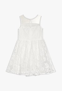 Vit spetsklänning med ärmlös design, blommönster, utsvängd kjol och genomskinlig baksida. Stängs med dragkedja bak.