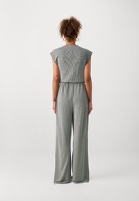 Une combinaison rayée grise à manches courtes, avec une taille élastique et des pantalons larges. Sa texture douce et sa coupe décontractée augmentent le confort.