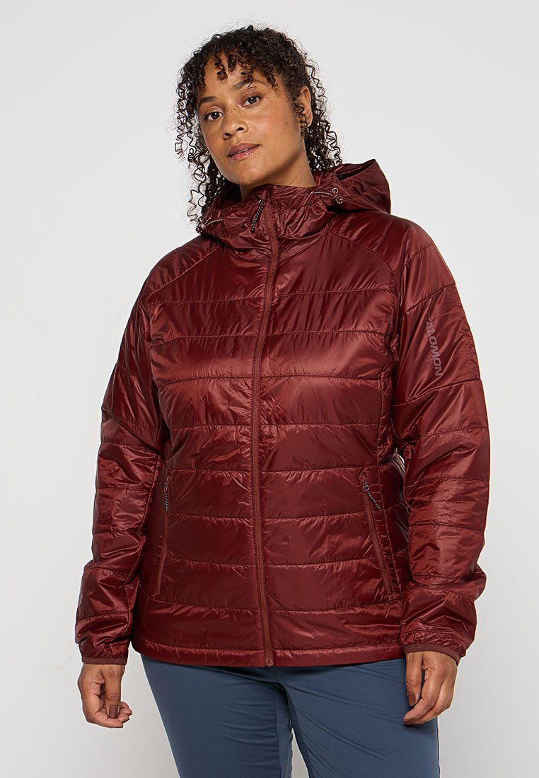 Chaqueta aislante burdeos con cierre frontal de cremallera, capucha ajustable y textura acolchada horizontal. Presenta bolsillos laterales y puños con orificio para el pulgar.