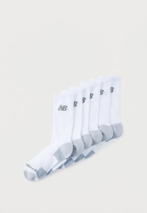 Sept paires de chaussettes blanches de sport avec talons et orteils gris, chacune arborant un logo "NB" noir près du haut.