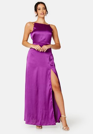 Abito maxi in raso viola con scollatura dritta, spalline sottili e uno spacco sul lato sinistro. Tessuto liscio, vita aderente e drappeggio elegante.