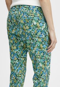 Byxor med blommönster i gröna, blå och gula färger. Tillverkade av lättviktsmaterial med elastisk midja och sidofickor.