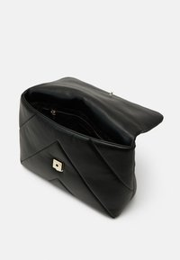 Borsa a spalla in pelle nera con design trapuntato, minuteria dorata e chiusura magnetica. L'interno presenta una tasca con zip per l'organizzazione.