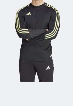 Black athletic top with long sleeves, featuring neon yellow stripes and a half-zip collar. Material appears smooth and fitted.