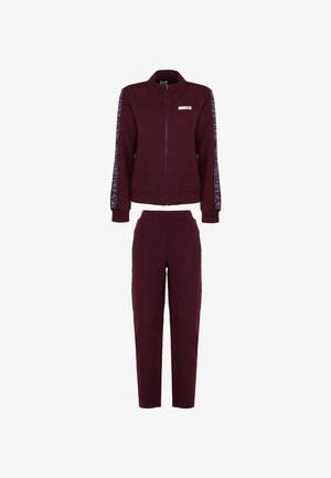 Burgundy-huopaluku, jossa on vetoketjullinen takki logovälikkeillä hihoissa ja vastaavat kapeat housut joustovyötäröllä.