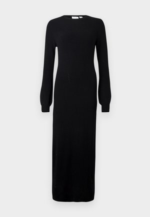 Vestido de punto negro de manga larga con cuello redondo, silueta recta y textura acanalada, que llega por debajo de los tobillos.