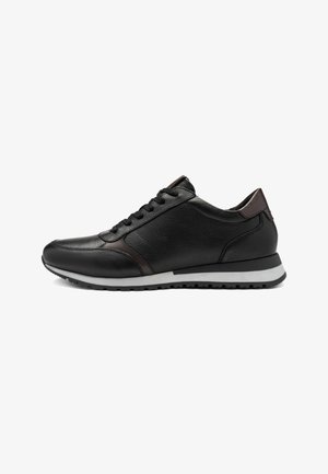 Black leather sneaker with brown accents, featuring a textured upper, six eyelet lacing system, and a white rubber sole. Minimalist design.