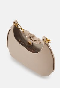 Vaaleanbeige nahkainen käsilaukku, jossa on pyöreä muoto, letitetty olkahihna, kultaiset yksityiskohdat ja vetoketjutasku sisällä. Siisti pinta ja minimalistinen muotoilu.