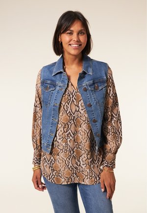 Denim vest met een fitted ontwerp, lichtblauwe kleur en klassieke knopen, gedragen over een bruin slangenprint blouse, in combinatie met een blauwe spijkerbroek.