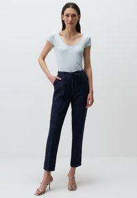 Jasnoniebieski prążkowany top z krótkim rękawem w połączeniu z ciemnoniebieskimi spodniami o wysokim stanie, posiadającymi sznurki i boczne kieszenie. Srebrne sandały na obcasie.