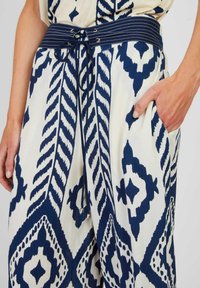 Pantalons à jambes larges à motifs bleu marine et blancs avec un tissu texturé. Dotés d'une taille rayée et d'une poche avant. Détail avec cordon de serrage inclus.