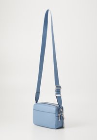 Jasnoniebieska torebka crossbody z faux skóry z zapięciem na zamek, regulowanym paskiem, gładką fakturą i srebrnymi akcentami.