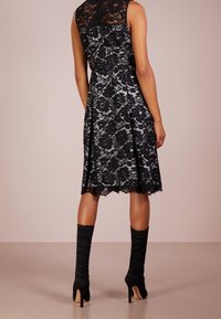 Musta pitsimekko, jossa on tiukka yläosa ja levenevä hame, jossa on aaltoileva helma. Yhdistettynä reittä yllättävän rypistettyihin mustiin saappaisiin.