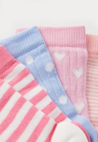 Cuatro pares de calcetines de lana: con rayas rosas y blancas, sólidos en azul claro con puntos blancos, sólidos en rosa con corazones blancos, y rosa claro con rayas.