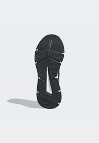 Suola di scarpa sportiva nera con un motivo testurizzato, caratterizzata da un particolare bianco laterale e scanalature strutturate per la trazione.