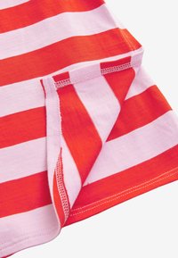 Rood en roze gestreepte stof met een zachte textuur, voorzien van contrasterende effen strepen. De randen hebben nette stiksels; de hoek is gevouwen.